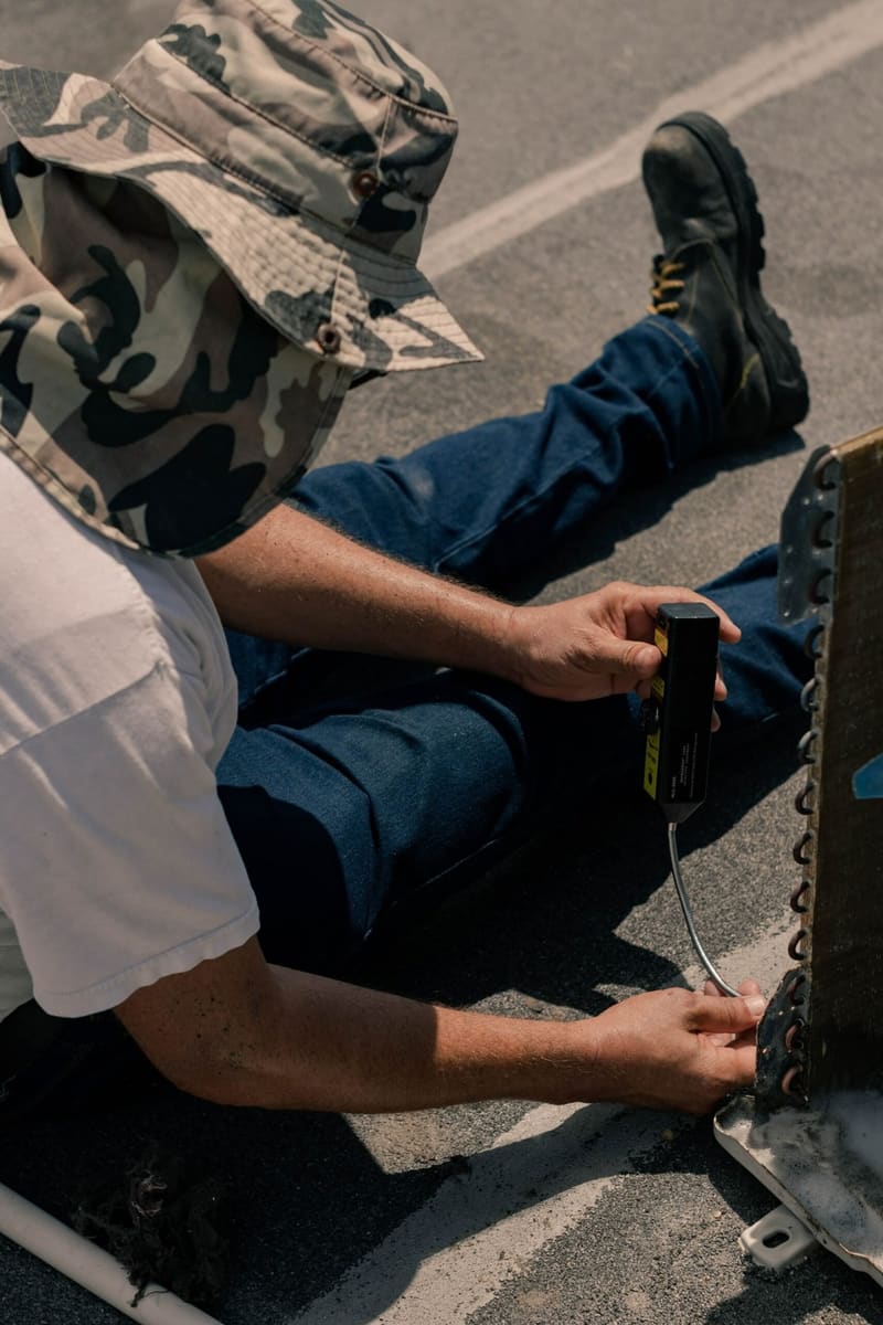 Air conditioning engineer checking system pressures with a gauge on an outdoor unit